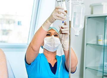 Person wearing scrubs, adjusting IV medication.